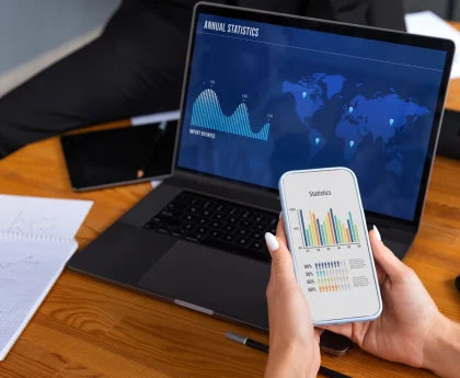 Professional reviewing trading graphs on phone and laptop with app development services in Bangalore.