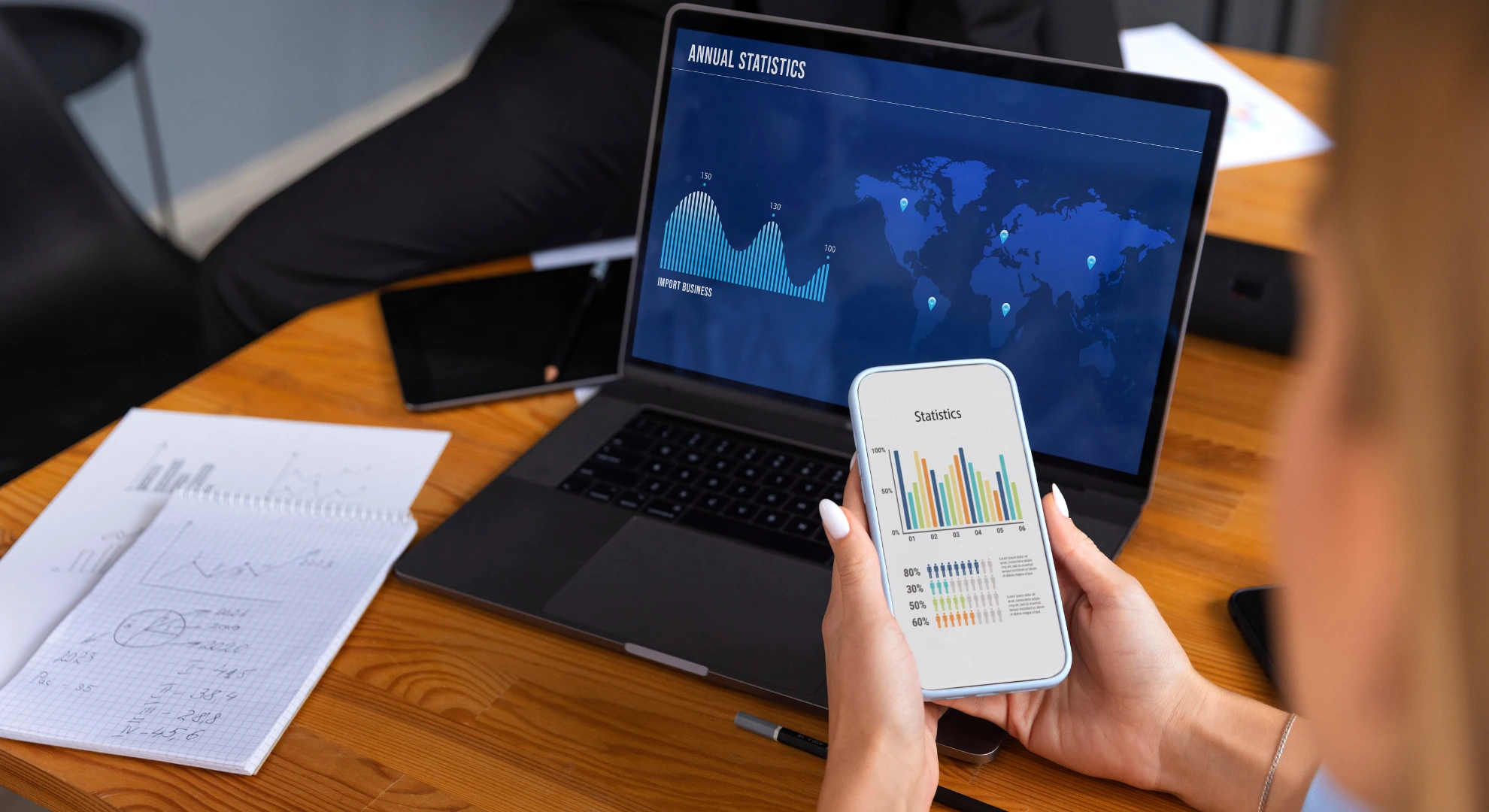 Professional reviewing trading graphs on phone and laptop with app development services in Bangalore.